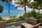 Lounge chairs on a wooden deck situated near the ocean, with palm trees on the horizon