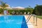 Loungers placed on the right and in the front of a pool with clean looking water on a sunny day.