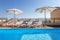 Loungers placed on the right and in the front of a pool with clean looking water on a sunny day.