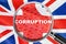Loupe focused on the word corruption on UK flag background. Corruption, financial concept in United Kingdom