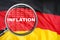 Loupe focused on the word inflation on Germany flag background. Inflation, tax, financial concept in Germany