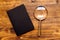 Loupe magnifying glass and notebook on wooden desk, top view