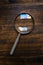 Loupe magnifying glass on wooden desk, top view
