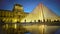 Louvre Pyramid reflection on water surface, silhouettes of tourists at museum