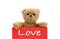 Love brown teddy bear holding with the two hands a red pink color note with the message â€œLove`