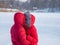 Love in the cold. A couple in red jackets hugging in the snow in winter