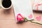 Love composition - coffee cup, gift box and rose on pink background, top view.