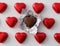 Love concept - close up of wrapped and unwrapped heart shape chocolate candies in red foil over white background