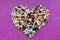 Love concept.Heart-shaped decoration from colorful pebbles on a purple background.choco rocks looks like pebbles