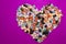 Love concept.Heart-shaped decoration from colorful pebbles on a purple background.choco rocks looks like pebbles