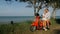 Love couple on red motorbike in white clothes on forest road trail trip. Two caucasian tourist woman and man kiss hugs