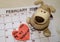 Love day - Paper red hearts marking 14 february Valentines day on white calendar with soft toy puppy