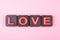 Love engraved in chocolate on colored background
