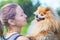 Love, friendship between owner and dog. smiling girl looking at handsome fluffy spitz. happy Pomeranian in hands of woman. female