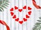 Love greeting composition with frame made red hearts, ribbons and palm leaves on wooden background.