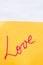 Love handwriting text close up isolated on orange paper with copy space. Writing text on memo post reminder