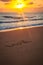 LOVE handwritten in sand on a beautiful beach in sunrise or suns