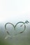 Love heart with arrow on a wet window. Closeup on foggy glass background