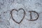 Love heart, carved in a concrete stone. filled with brown needles, and a capital letter D