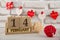 Love holiday decorations. Wooden cube calendar with 14 february date staying on white background near rattan balls and small