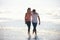Love, hug and couple at a beach walking, calm and bonding on ocean adventure together. Travel, sunset and people at sea