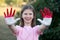 Love Indonesia. Child girl show hands painted in Indonesia flag colors. Indonesian patriotism concept. Indonesian