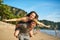 Love means having fun together. Portrait of a happy young man giving his girlfriend a piggyback ride on the beach.