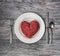 A love of meat, fresh ground beef in the shape of a heart on a white plate with cutlery and grey wood background