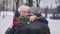 Love at old ages. Elderly couple hugging in the park. Woman holding red roses