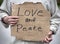 Love and Peace handwritten cardboard sign, man holding, closeup