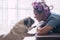 Love and pet therapy concept with home scene woman and best friend dog kissing and looking - romantic pug and female situation -