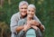 Love, portrait and elderly couple hug in a forest for hiking, relax and walking in nature on blurred background. Face