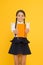 Love reading for pleasure. Cute small schoolchild holding reading book on yellow background. Adorable little girl learn