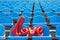 Love red foil balloon on blue stadium seats. Letter-shaped balloons forming the word love lifestyle background