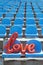 Love red foil balloon on blue stadium seats. Letter-shaped balloons forming the word love lifestyle vertical background