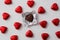 Love, relationship and broken heart concept - close up of wrapped and unwrapped heart shape chocolate candies in red foil over