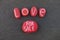 Love for sale message with a composition of red colored stones over black volcanic sand