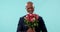 Love, smelling and a senior black man with flowers for valentines day on a blue background in studio. Portrait, smile