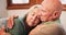 Love, support and hug with a senior couple on a sofa in the living room of their retirement home together. Safety, trust