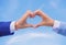 Love symbol concept. Hand heart gesture forms shape using fingers. Hands put together in heart shape blue sky background