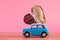 Love Takes the Wheel: Retro Toy Car Carrying a Heart on a Pink Background