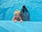 Love to animals - little girl posing with dolphin in pool of dolphinarium