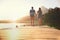 Love under a beautiful sunset. Rearview shot of an affectionate young couple standing on a dock at sunset.