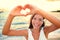 Love vacation - woman showing heart on beach