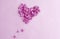 Love wishes card: a heart made of lilac flowers on a pastel background, top view, space for text