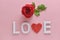 LOVE word made from medicine pills and red rose on pink background. Concept of Valentine`s Day