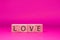 Love word , Text on wooden block object on pink background and copy space - Pink Valentine celebrate concept