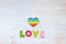 LOVE word in wood letters and rainbow heart shape pillow on wood vintage board. Valentines day concept. Mockup for LGBT