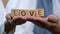 Love word on wooden cubes in happy couple palms, trust and support in relations