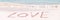 Love written on the white sand of an idyllic beach panoramic Valentines day banner